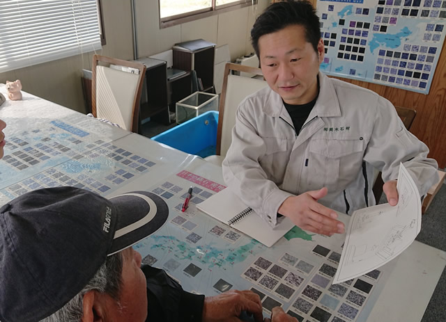 筒木社長が墓石について図面を見せながらお客様に説明している写真